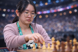 Tan Zhongyi, chinesische Schachspielerin, führt während einer Partie bei einem internationalen Turnier konzentriert einen Zug mit einer weißen Figur aus.