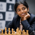 A young female chess player in a dark blazer sits at the board with a slight smile, resting on her hand, while chess symbols and the atmosphere of a tournament hall can be seen in the background.