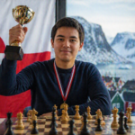 Ένας σκακιστής κρατά ένα χρυσό κύπελλο πάνω από μια σκακιέρα, με φόντο τη σημαία της Γροιλανδίας και χιονισμένα βουνά, συμβολίζοντας τη νίκη στο εθνικό πρωτάθλημα.