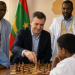 FIDE-Exekutivdirektor Victor Bologan spielt Schach mit jungen Teilnehmern eines Schachprogramms in Mauretanien. Kinder und Mitglieder der lokalen Gemeinschaft versammeln sich um das Schachbrett und diskutieren die Entwicklung der Schachbildung und die Popularisierung des Spiels im Land.